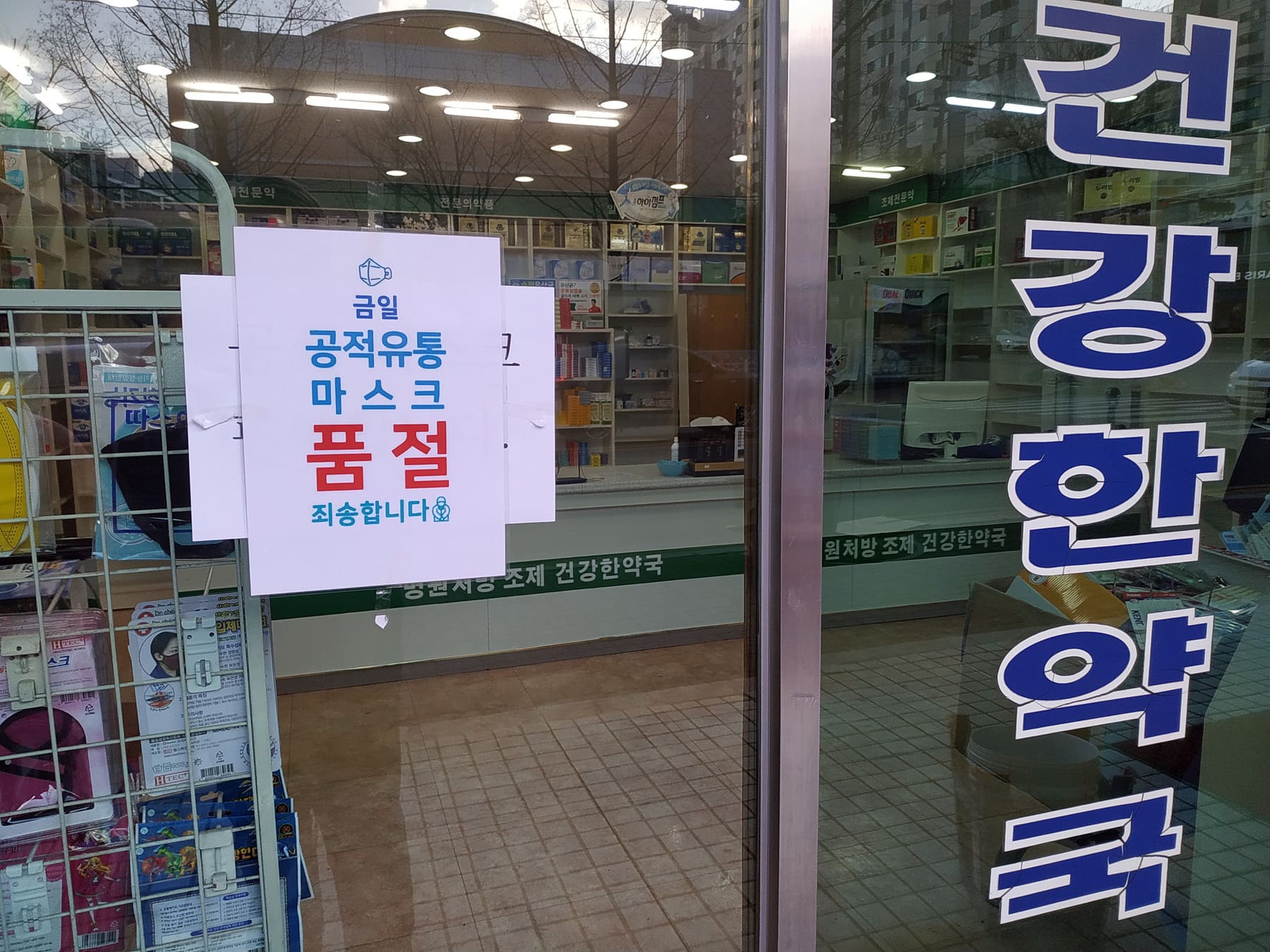 A pharmacy door in South Korea with a notice reading 품절 죄송합니다, sold out, sorry