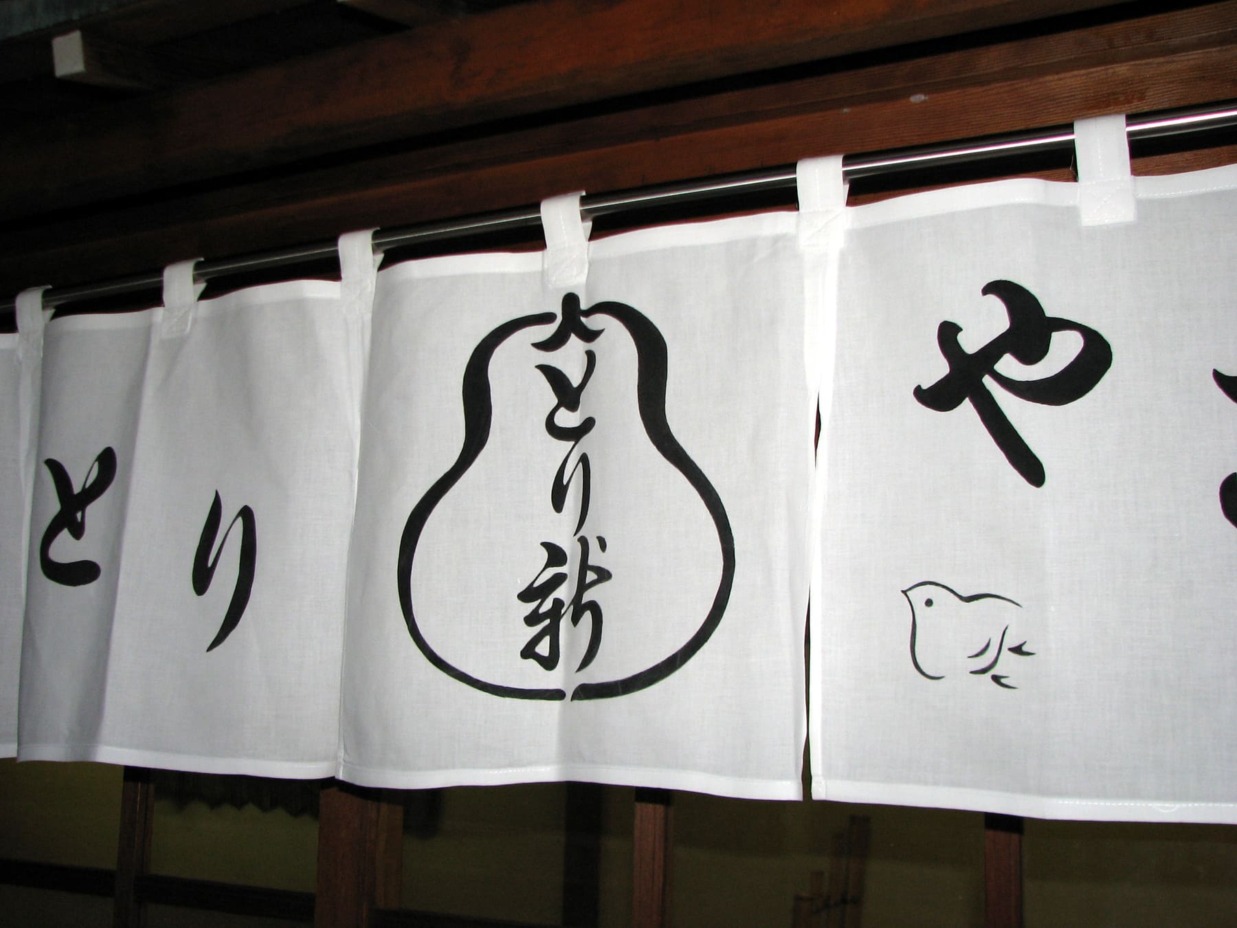 A white noren shop curtain with hiragana and a kanji mark at a yakitori restaurant