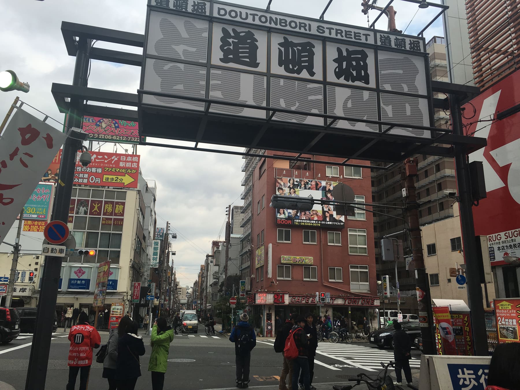 The Dotonbori Street gate sign in Osaka in kanji with a busy street behind