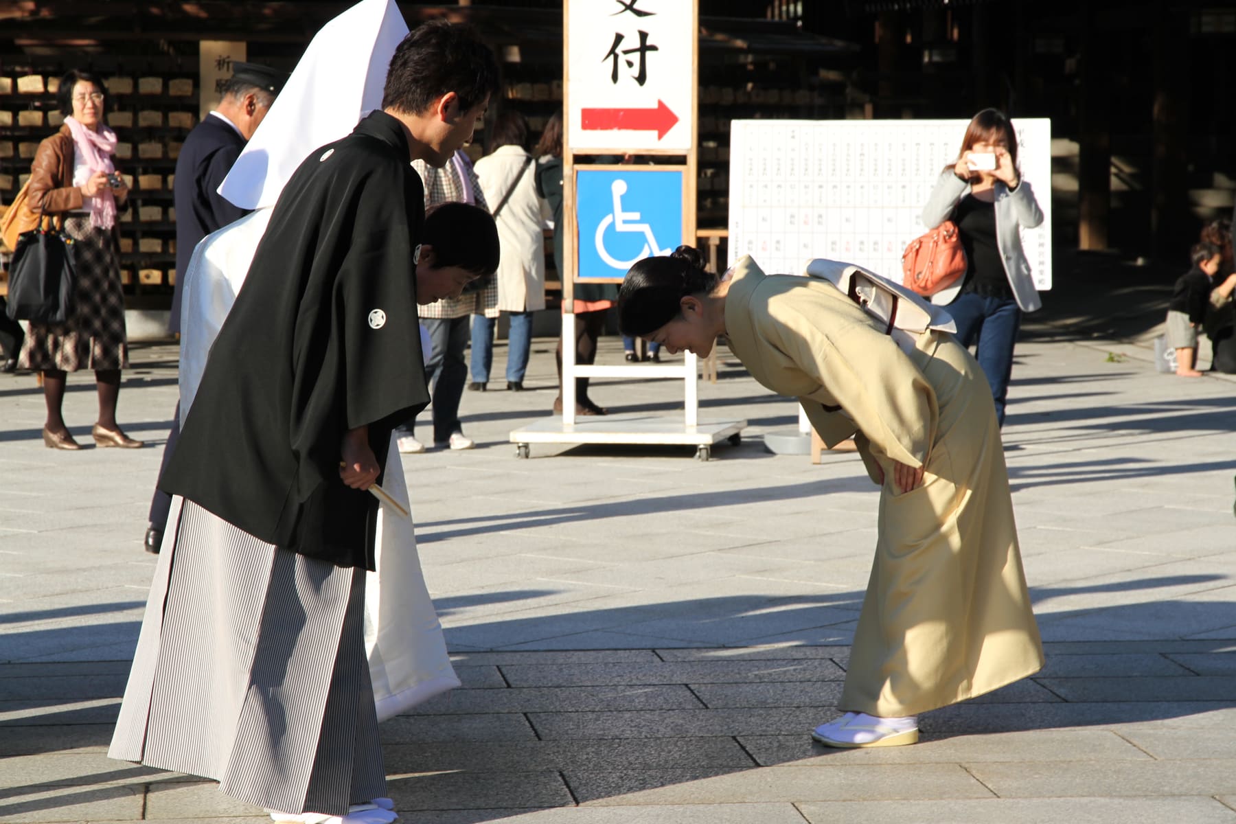 Two people in traditional Japanese dress bowing to each other in a plaza