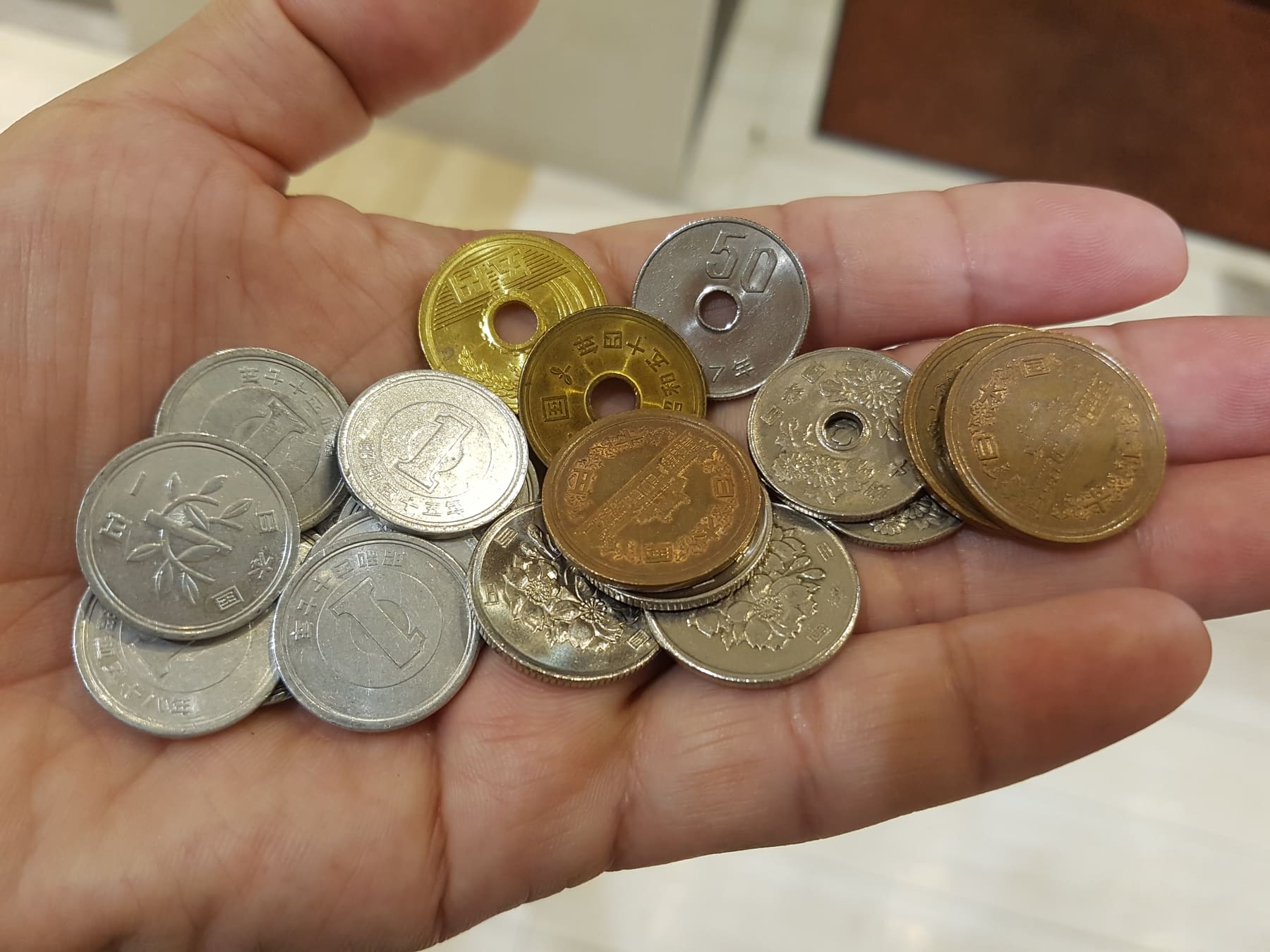 A hand holding a pile of Japanese coins