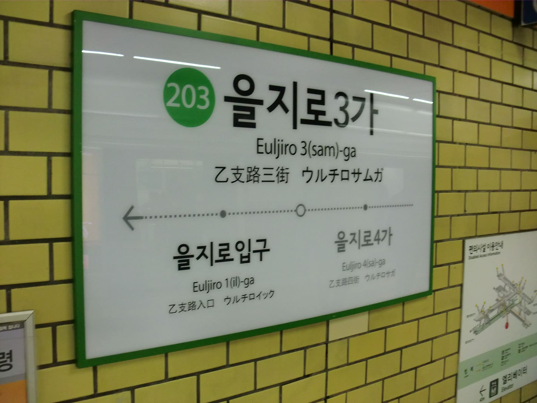 A Seoul subway station name sign in Hangul with Roman letters and Chinese characters beneath