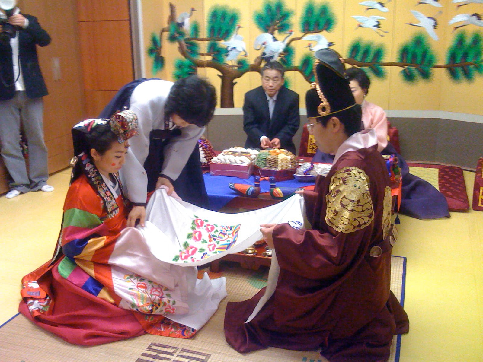 A newlywed couple in traditional dress offering a bow-ceremony to elders at a Korean wedding pyebaek