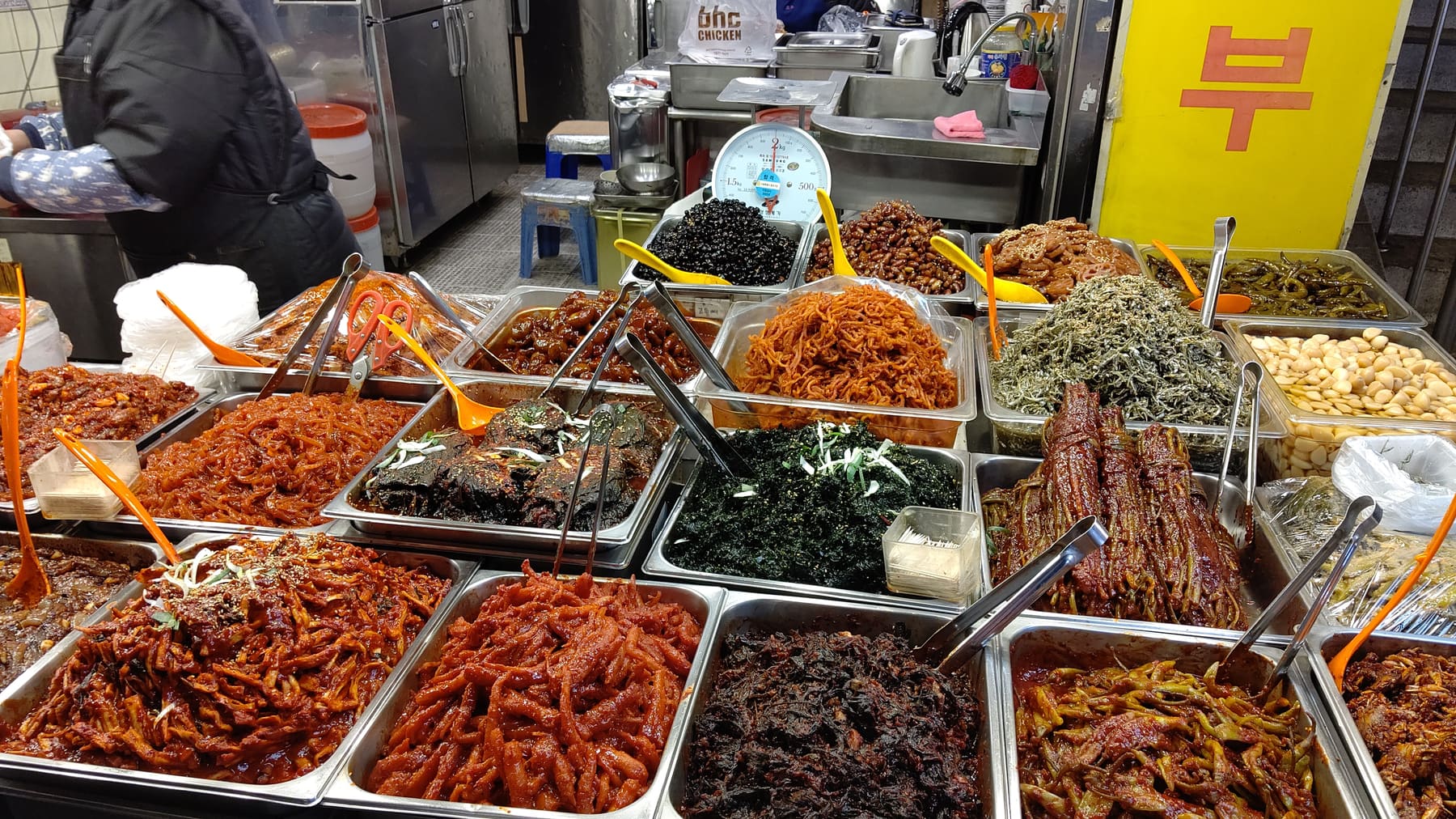 Trays of kimchi and seasoned side dishes at a banchan stall in Gwangjang Market