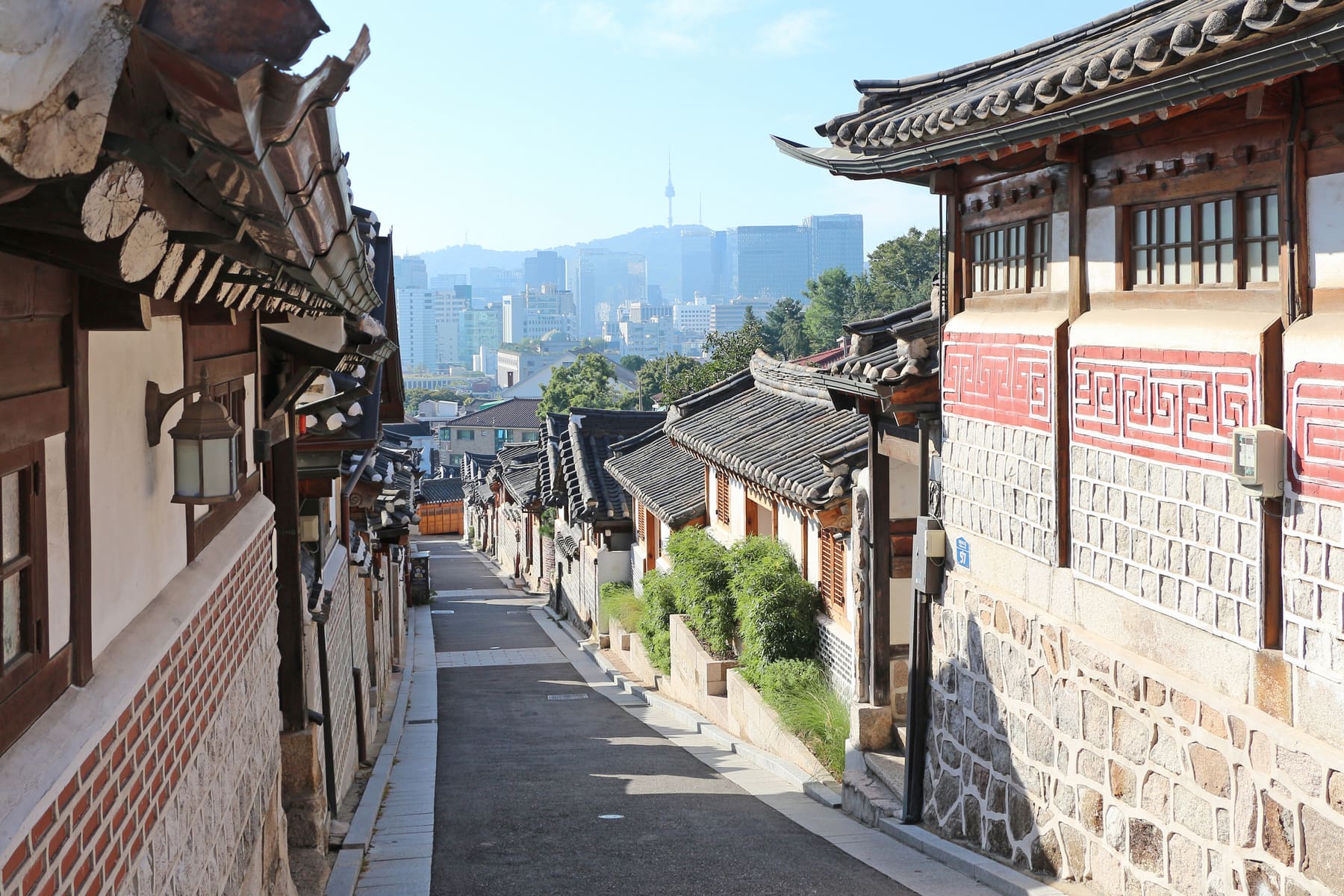A narrow hanok alley in Bukchon Hanok Village with N Seoul Tower on the skyline