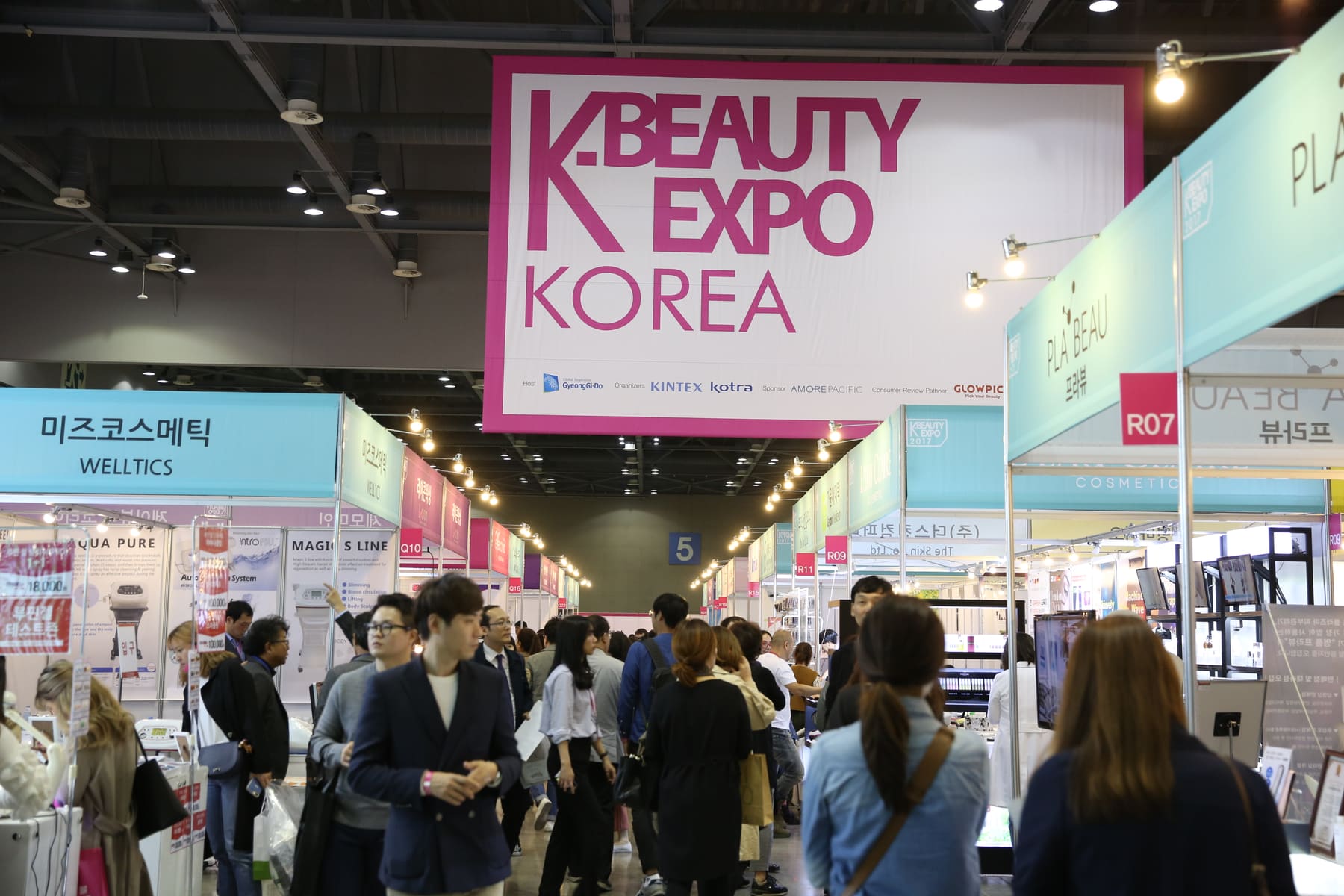 Visitors walking between cosmetics booths under the K-Beauty Expo Korea sign at KINTEX